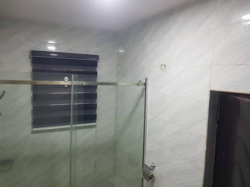 La salle de bains est pourvue d'une cabine de douche avec une porte en verre. dans l'établissement 3JD Lavishly Furnished 1-Bed Apt, à Lagos