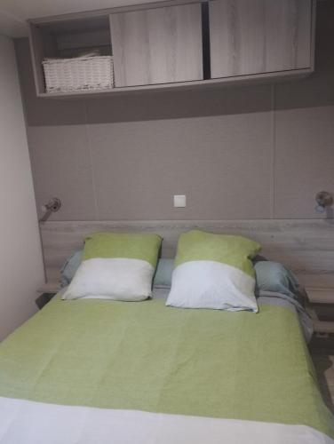 a bed with two green and white pillows on it at Mobil-home tout confort à 300m de l'océan in Saint-Brevin-les-Pins