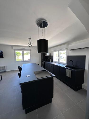 uma cozinha com uma ilha negra numa sala de estar em Design Therapy em Lavérune
