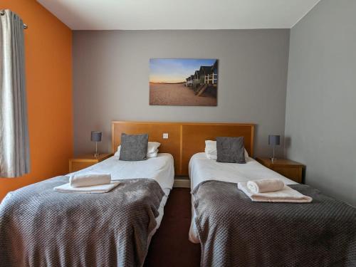 2 camas en una habitación con paredes de color naranja en The Earl Of Derby en Cambridge