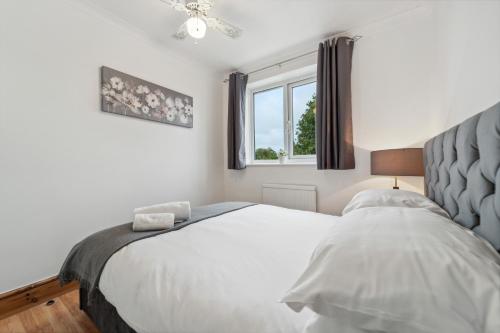 a bedroom with a white bed and a window at 5 double beds in a detached house in Cheshunt in Cheshunt