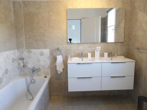 Un baño con lavabo, bañera y espejo. en Villa de standing, en Calvi