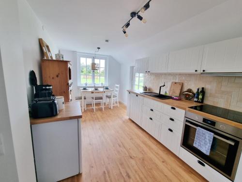 a kitchen with white cabinets and a wooden floor at 200 Jahre altes Landhaus mit Tieren in Goldenstedt