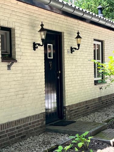 a brick house with a black door and lights at Guesthouse 't Oeyenbos in Knegsel