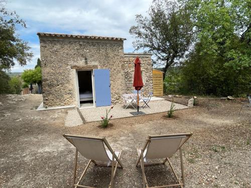 a patio with two chairs and a red umbrella at La Parenthèse du Var - Chambre d'hôtes petits déjeuners inclus et terrasse ombragée in Saint Antonin du Var