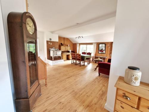 a living room with a clock and a dining room at 200 Jahre altes Landhaus mit Tieren in Goldenstedt