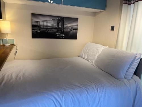 Un dormitorio con una cama blanca con una foto en la pared en Studio Annex en Cottenham