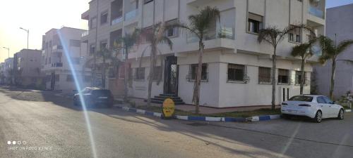 um carro branco estacionado ao lado de um edifício com palmeiras em Location de vacances à la plage de Bouznika em Bouznika
