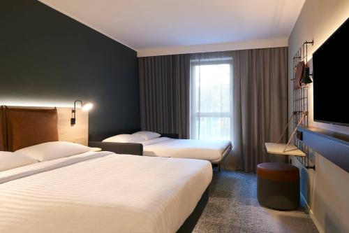 a hotel room with two beds and a flat screen tv at Moxy Essen City in Essen