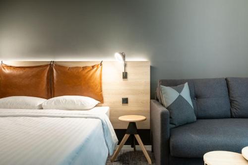 a bedroom with a bed and a couch at Moxy Essen City in Essen