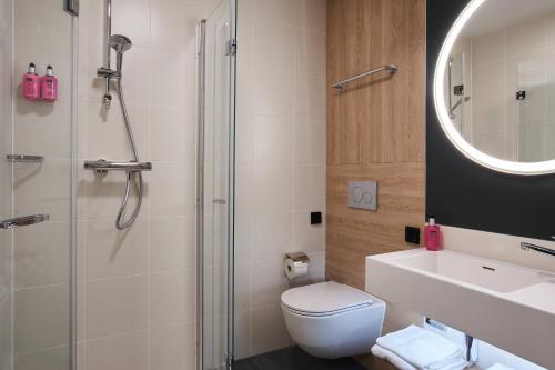 a bathroom with a shower and a toilet and a sink at Moxy Essen City in Essen