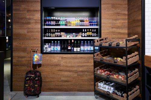 a drink station with a suitcase and a drink refrigerator at Moxy Essen City in Essen