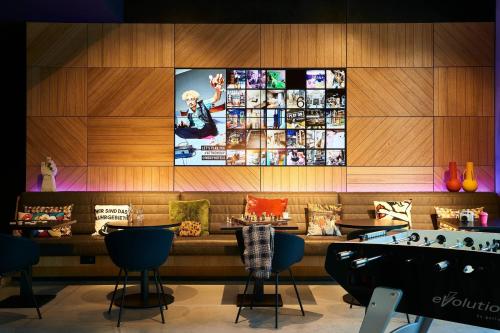 a restaurant with a large tv on the wall at Moxy Essen City in Essen