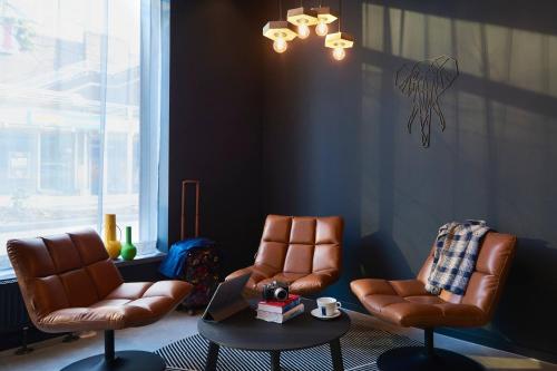 a living room with two chairs and a table and a window at Moxy Essen City in Essen