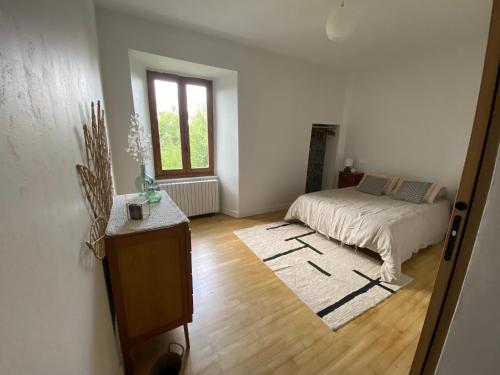 a white room with a bed and a window at La maison de Marie in Junhac