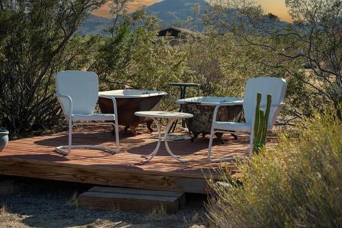 two chairs and a table on a wooden deck at The Raven House - Renovated Homestead Cabin in Joshua Tree