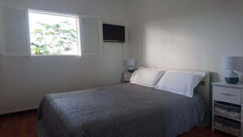 a bedroom with a bed with white pillows and a window at La Minaude in Saint-Denis
