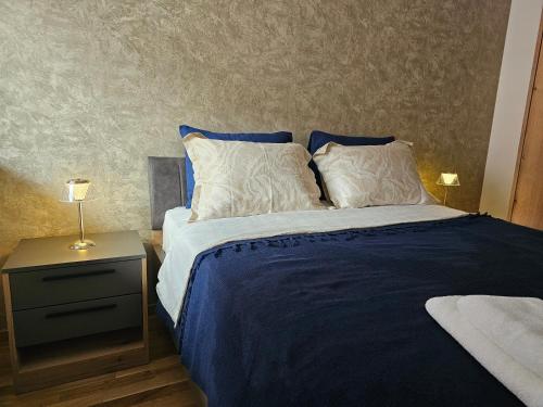 a bedroom with a bed with blue sheets and a nightstand at Sun&Moon Apartments in Novi Sad