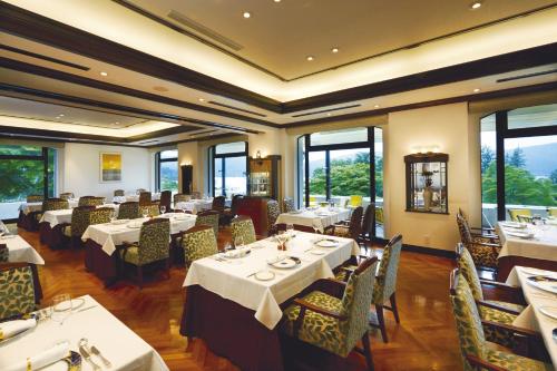 un comedor con mesas, sillas y ventanas en Odakyu Hotel de Yama, en Hakone