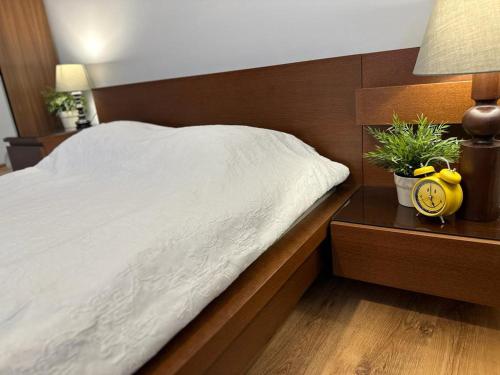 a bed with a white blanket and a clock on a night stand at Apartament przy Rynku in Poznań