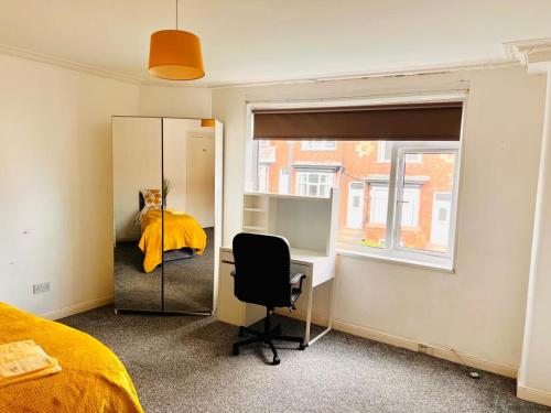 Private Room close to Leeds University and City centre في ليدز: غرفة نوم مع مكتب وسرير ومرآة