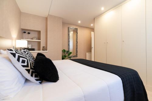1 dormitorio con cama blanca y almohadas blancas y negras en Elegante Apartamento Centrico, en Vigo