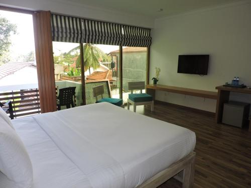 a bedroom with a bed and a balcony with a television at Binnacle Negombo in Negombo