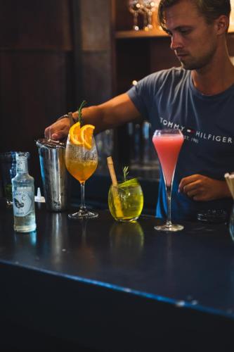 a man sitting at a bar with three cocktails at BOHO Bohemian Boutique Hotel in Willemstad