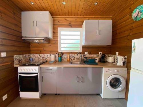 a kitchen with white appliances and a wooden wall at Kaz bleu karaibes in Sainte-Anne