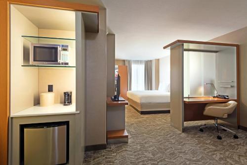 um quarto de hotel com um quarto com uma cama e uma secretária em SpringHill Suites Louisville Downtown em Louisville