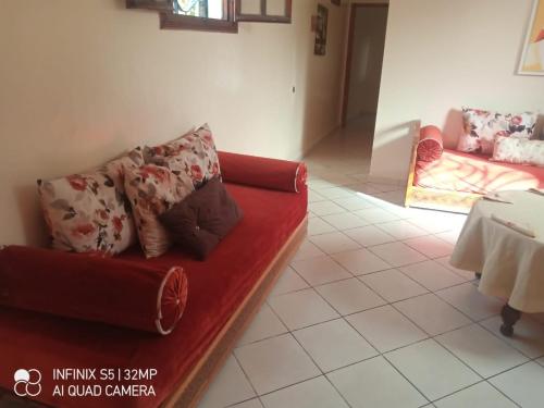 sala de estar con sofá rojo y mesa en شقة ببزنيقة, en Bouznika