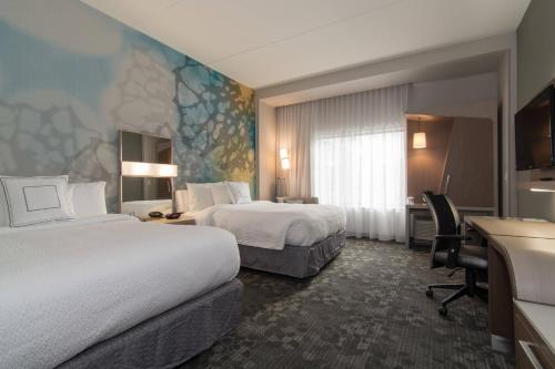 a hotel room with two beds and a desk at Courtyard by Marriott Raleigh-Durham Airport/Brier Creek in Raleigh