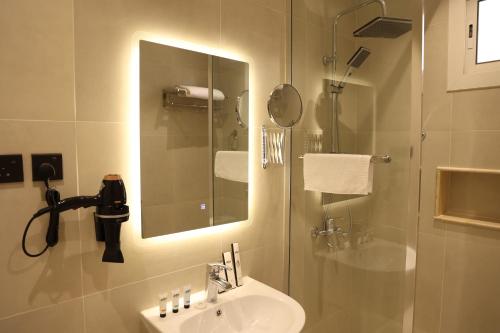 ein Bad mit einem Waschbecken und einer Dusche mit einem Spiegel in der Unterkunft نيلوفر - Nilover in Tabuk