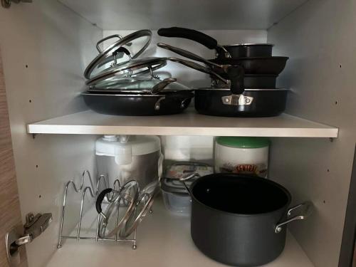 a shelf with pots and pans and other kitchen utensils at Condo Unit in BGC Taguig Manila with FREE Covered Parking & WiFi in Manila