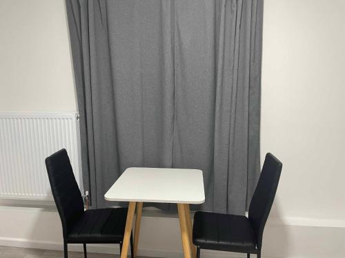 a white table and two chairs in front of a curtain at Studio flat private bathroom wc and kitchenette in London