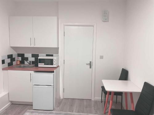 a kitchen with white cabinets and a white door at Studio flat private bathroom wc and kitchenette in London