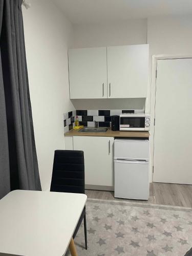 a small kitchen with white cabinets and a table at Studio flat private bathroom wc and kitchenette in London