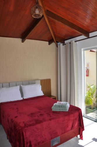 a bedroom with a bed with a red blanket at Suites Bougainville in Cavalcante