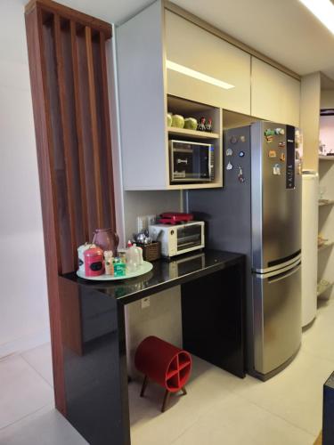 a kitchen with a black counter and a refrigerator at Genipabu Summer House Guarajuba in Guarajuba