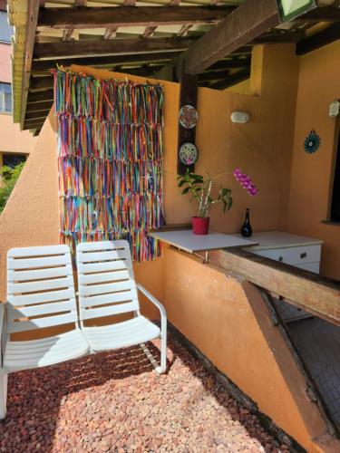 two white chairs on a patio with a colorful curtain at Genipabu Summer House Guarajuba in Guarajuba
