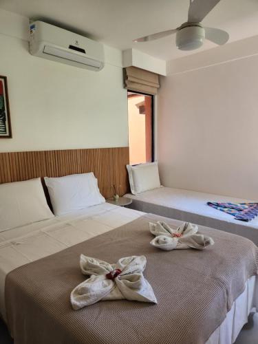 two beds with towels on them in a bedroom at Genipabu Summer House Guarajuba in Guarajuba