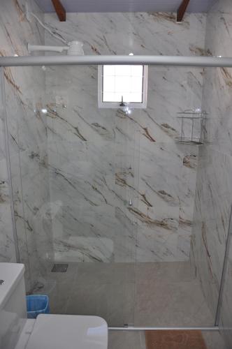 La salle de bains est pourvue d'une douche avec une porte en verre. dans l'établissement Suites Bougainville, à Cavalcante