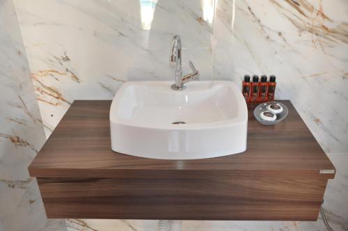 a bathroom with a white sink and a wooden counter at Pousada Suites Bougainville in Cavalcante