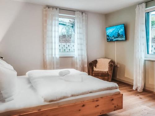 a bedroom with a bed and a window and a chair at ZWEITE HEIMAT - Alpine Garden Retreat in Zillertal, presented by AlpenLuxus in Fügen