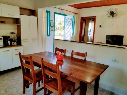 - une table en bois dans une cuisine avec un vase rouge dans l'établissement Casas de Campo Beija-Flor & Bem-Te-Vi, Mata Atlântica, Juquitiba, SP, à Juquitiba