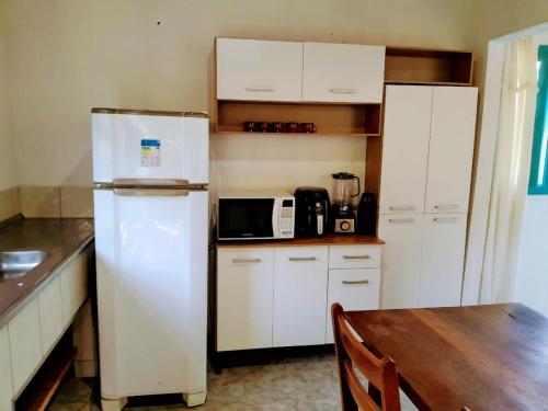 cocina con armarios blancos, nevera y mesa en Casas de Campo Beija-Flor & Bem-Te-Vi, Mata Atlântica, Juquitiba, SP en Juquitiba