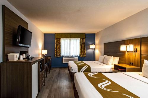 a hotel room with two beds and a flat screen tv at Quality Inn & Suites in Tulare