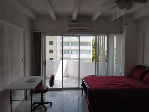 a bedroom with a bed and a desk and a window at Fresca estancia en zona Dorada con Alberca/Playa! in Acapulco