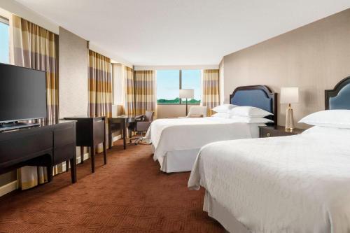 um quarto de hotel com duas camas e uma televisão de ecrã plano em Sheraton Baltimore North em Towson