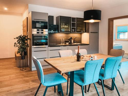 eine Küche und ein Esszimmer mit einem Holztisch und blauen Stühlen in der Unterkunft AlpenLuxus' RUHESTUBE with balcony & car park in Fügen